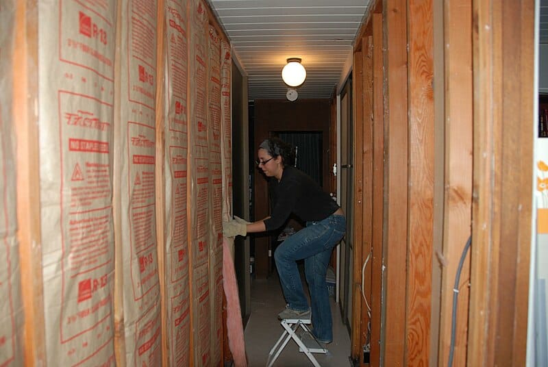 Tradewoman installing wall insulation.