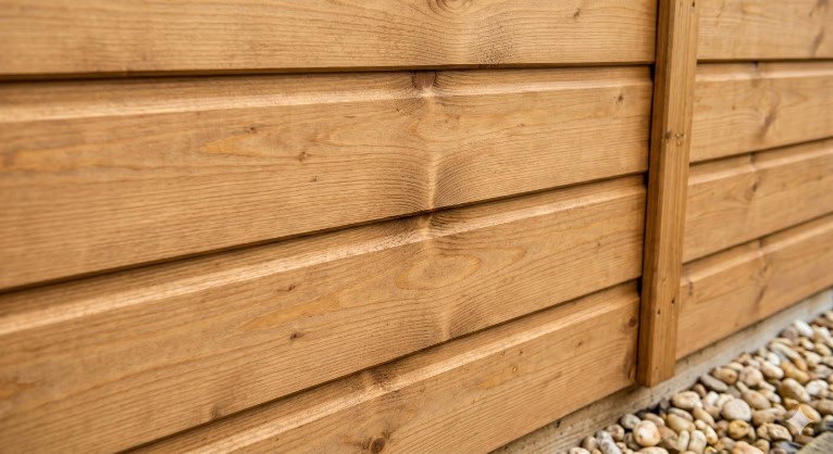 A close-up view of interlocking, natural-grain wooden tongue and groove cladding panels.