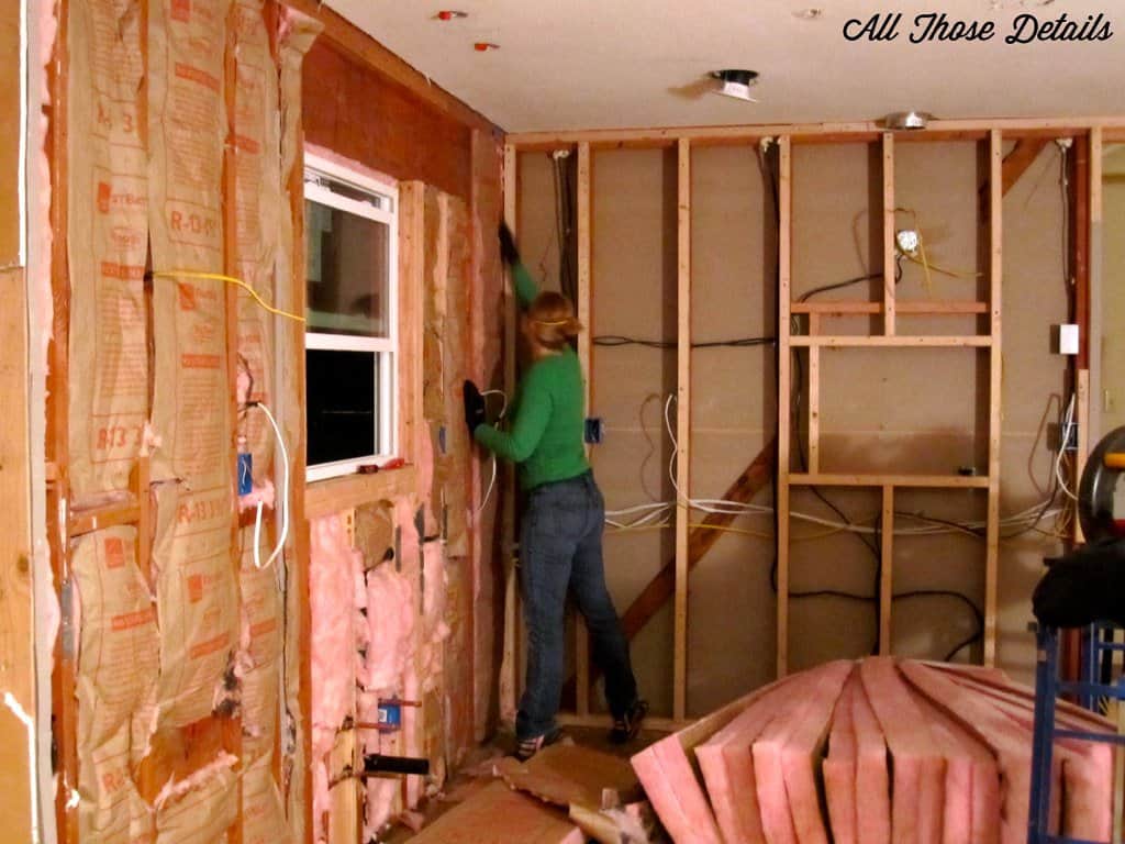 A person installing insulation in a wooden building