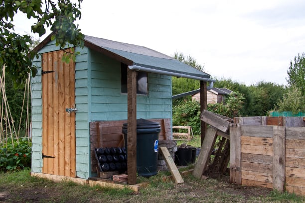 Wooden shed painted in blue positioned in a small allotment garden