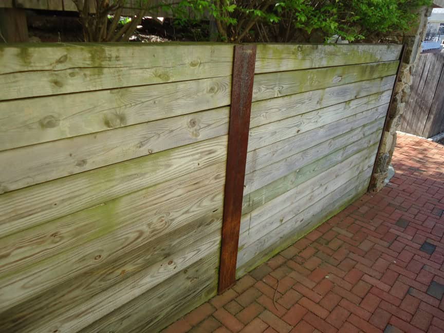 Retaining wall built with vertical I-beams and pressure-treated lumber.