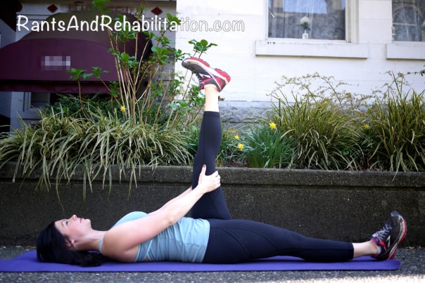 Woman in activewear performing ‘Hamstring Stretch’ on her yoga mat outdoors.