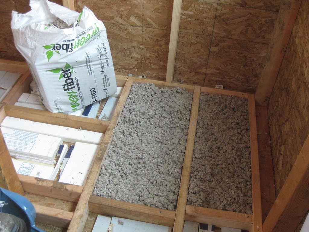 A shed’s floor being filled with insulation between the original floor.