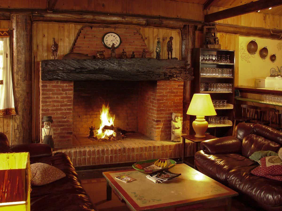 Brick fireplace with burning logs in cosy cabin cottage living room.