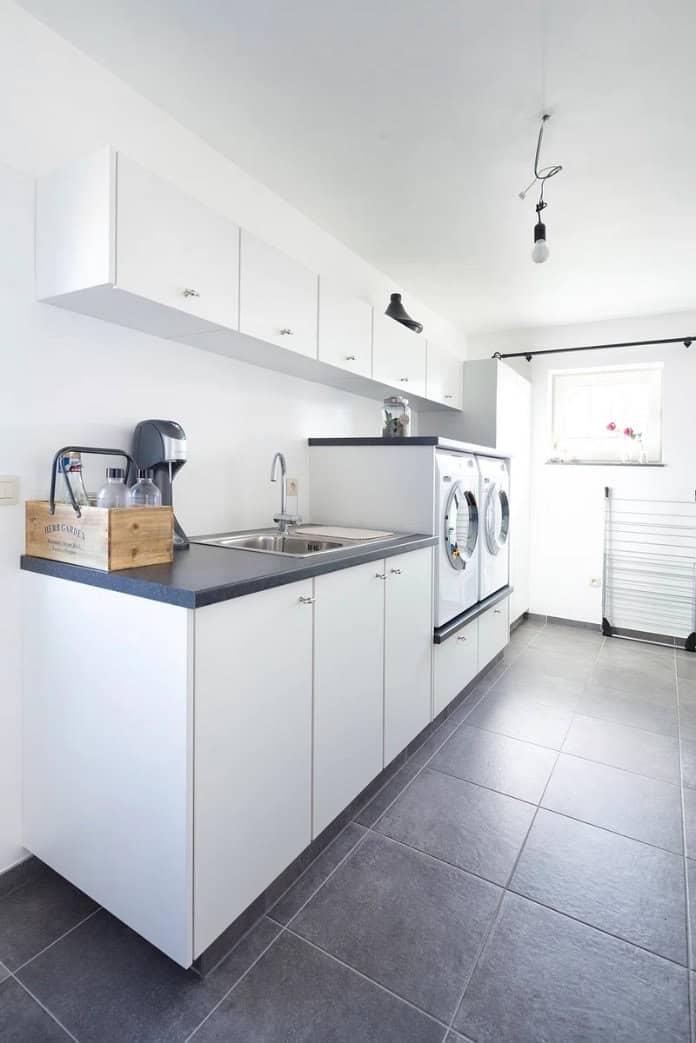 A laundry room with a countertop and sink, overhead cabinets, and a washer and dryer placed side by side.