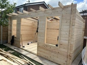 A nearly completed log cabin with just the roof, windows and doors left to install