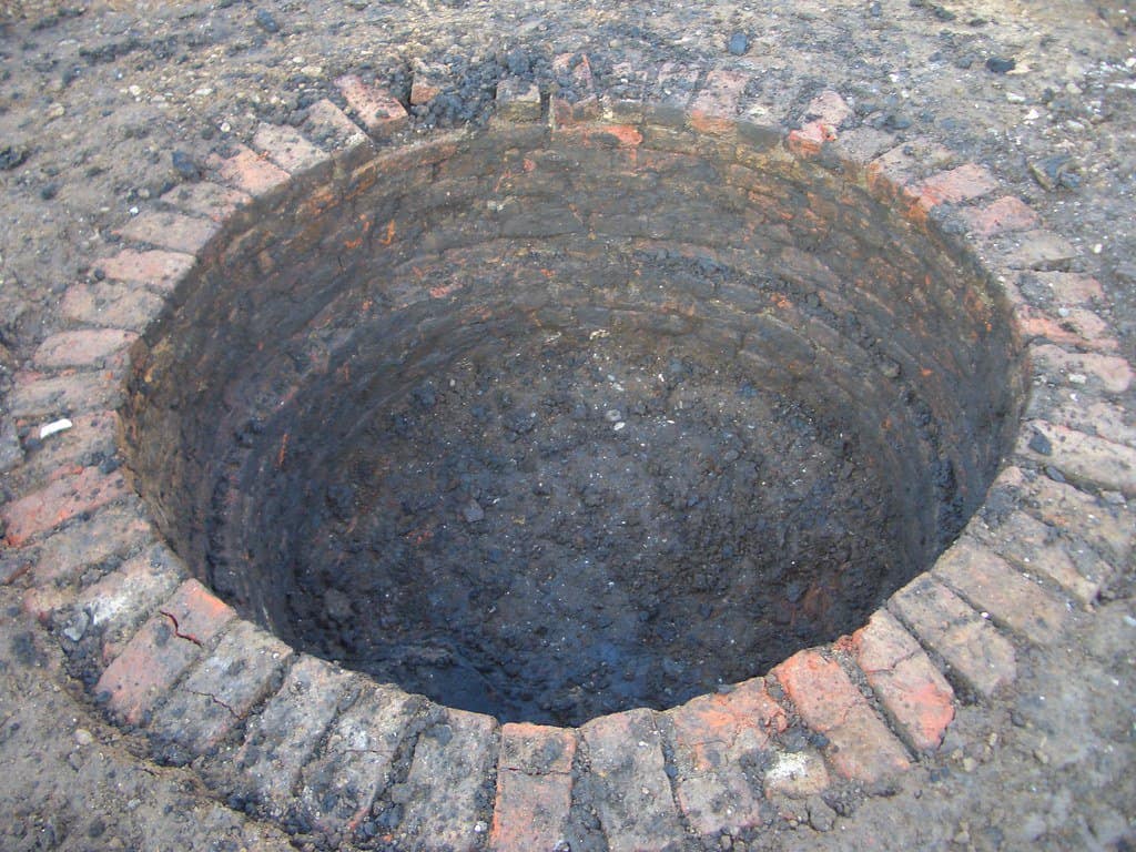 A garden soakaway lined with bricks, designed to manage excess rainwater.