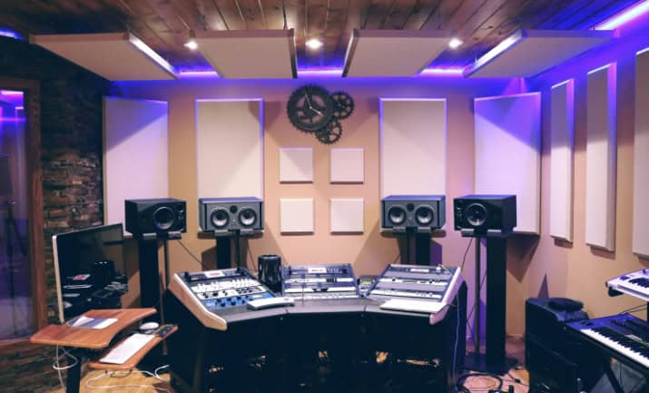 A recording studio with ultraviolet fluorescent lights featuring a control panel and microphone setup.