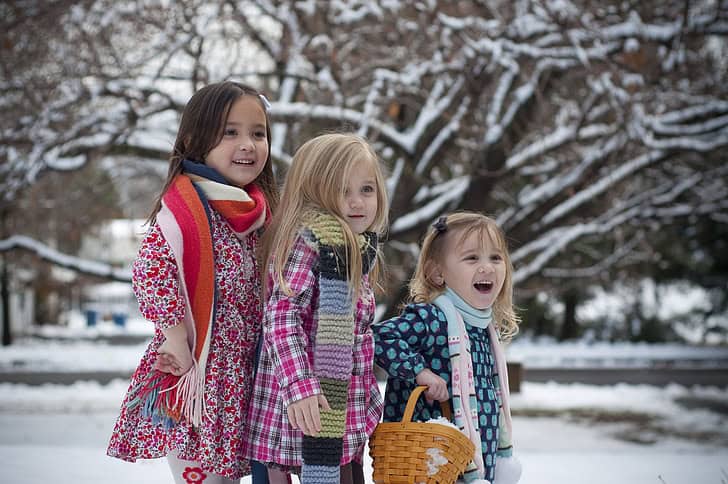 Three girls wearing coats and enjoying the snowy winter outdoors.