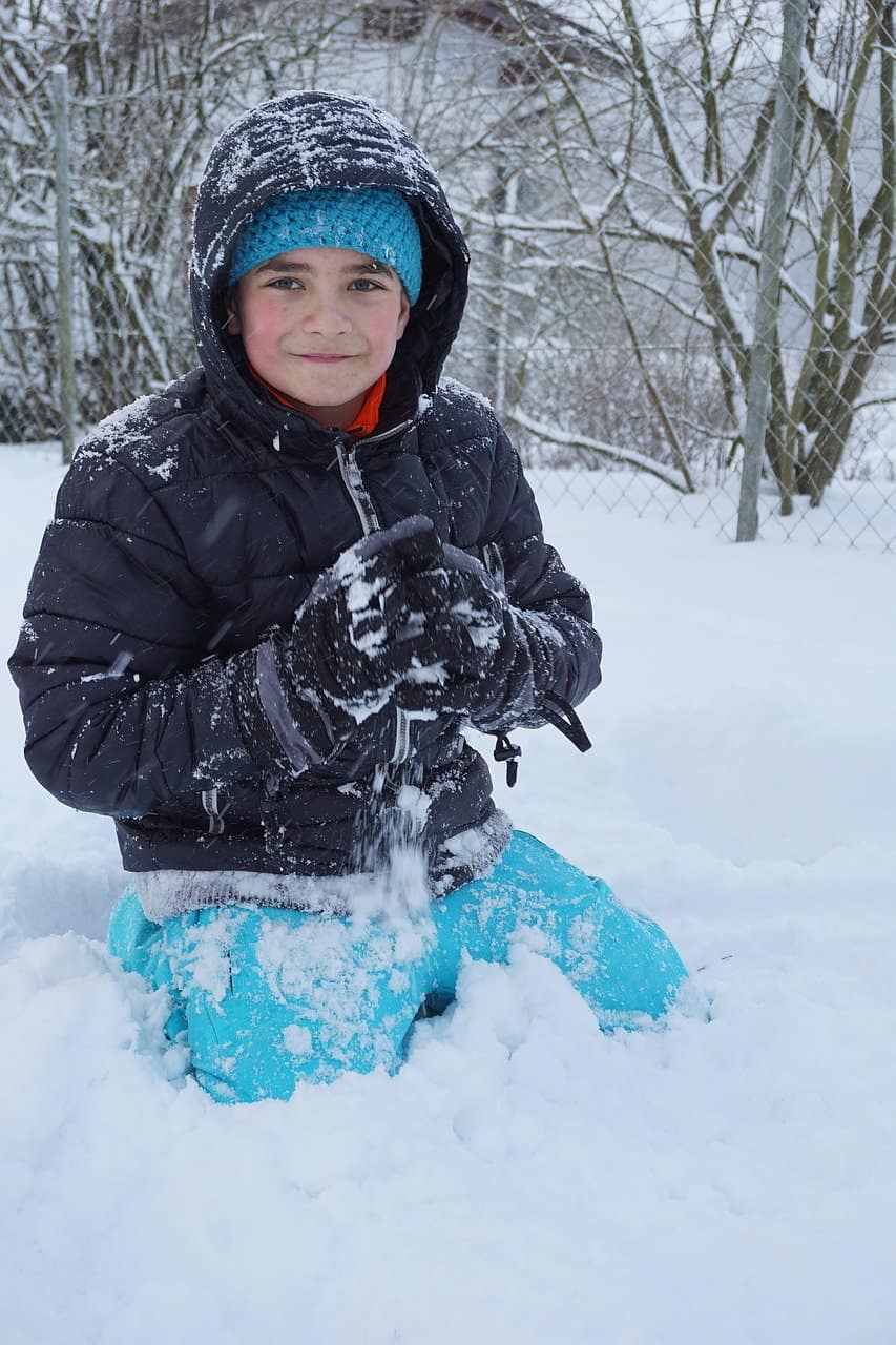 A boy enjoying a snowball fight in the winter.