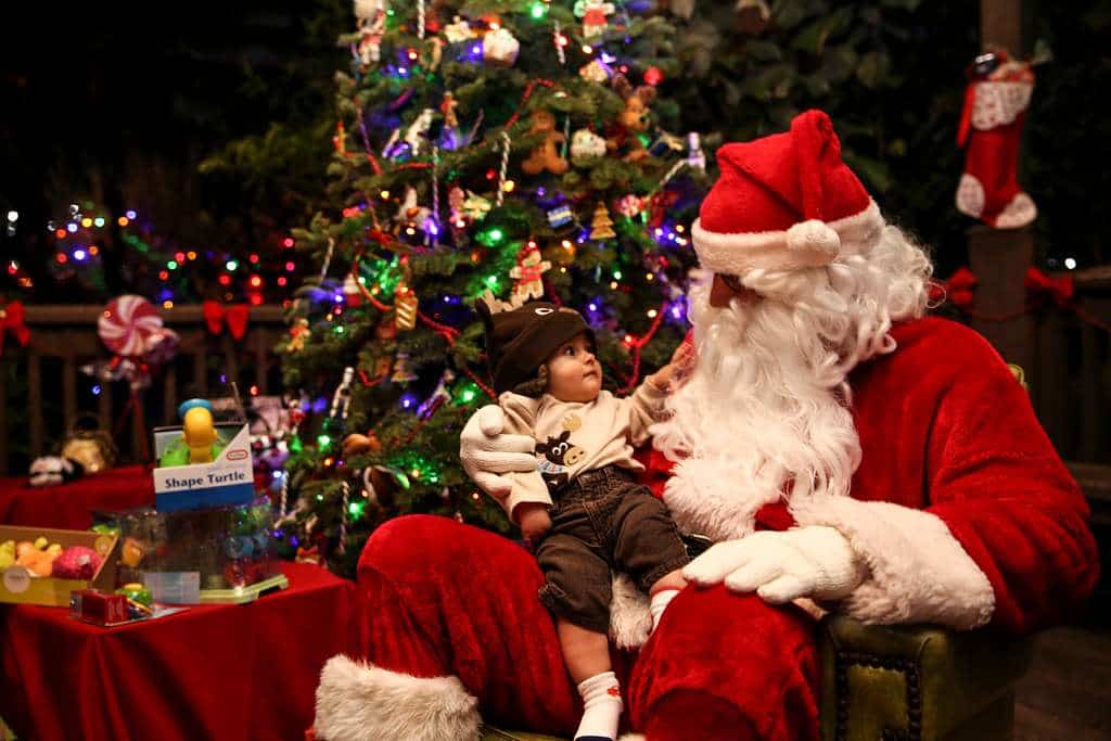 A child sitting on Santa Claus's lap, with Santa dressed in his traditional red suit.