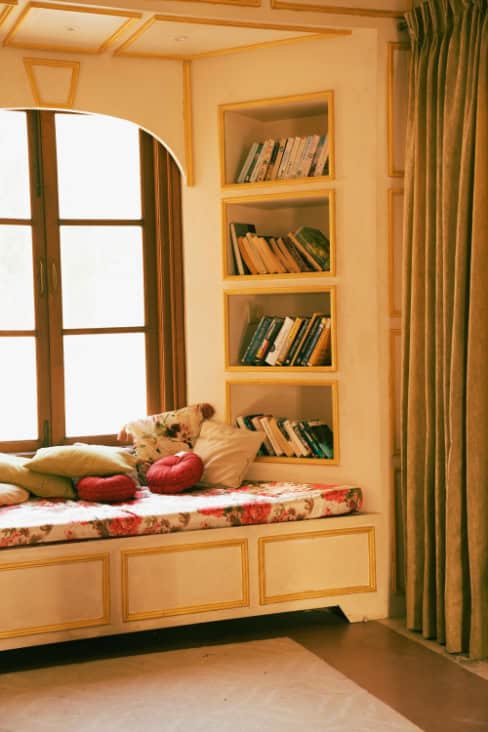 A bench seat with a bookshelf in a window bay.