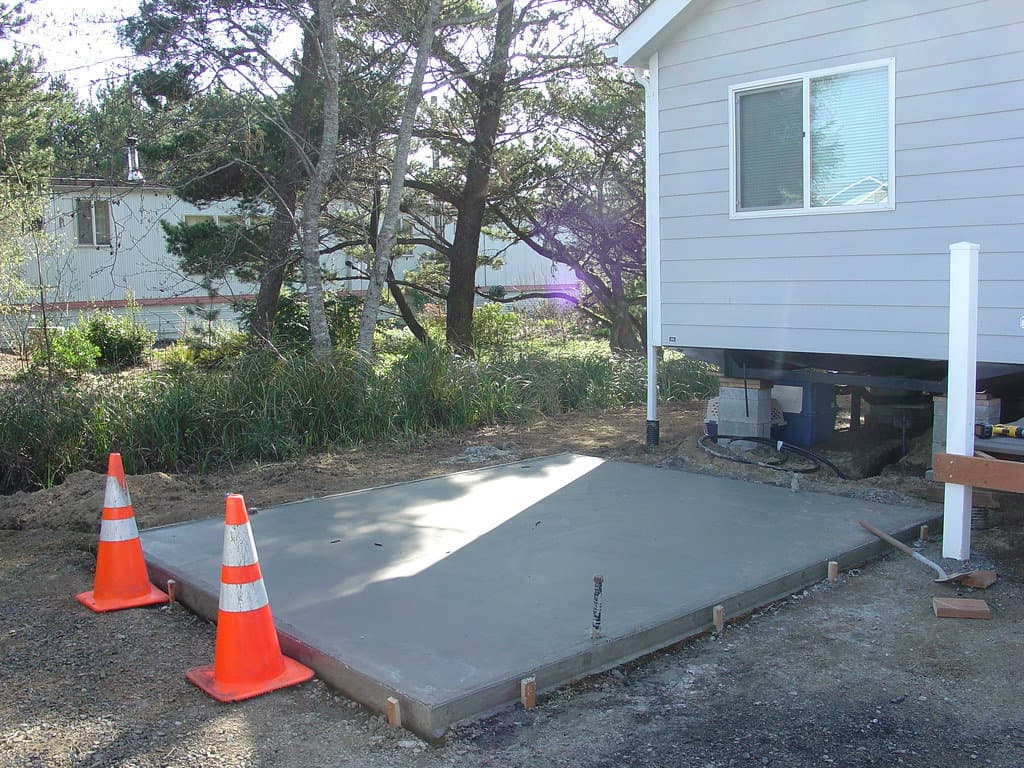 Curing a concrete slab in the backyard for a shed, with hazard cones placed for caution.