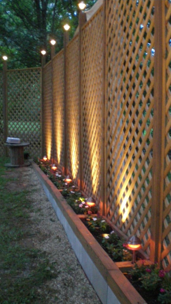 Wooden lattice fencing, lit with uplighting.