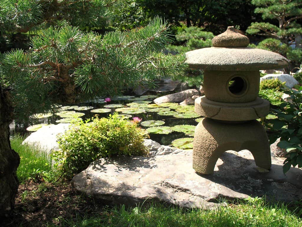 Stone Japanese lantern near a Koi garden pond.