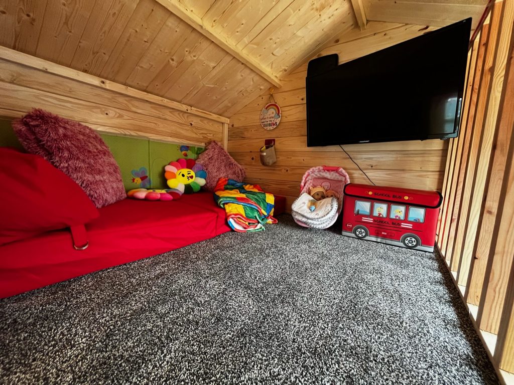 Wooden playhouse interior with a TV installed on the wall in the upstairs section
