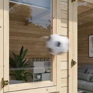 A log cabin with a casement window, resisting the impact of a football