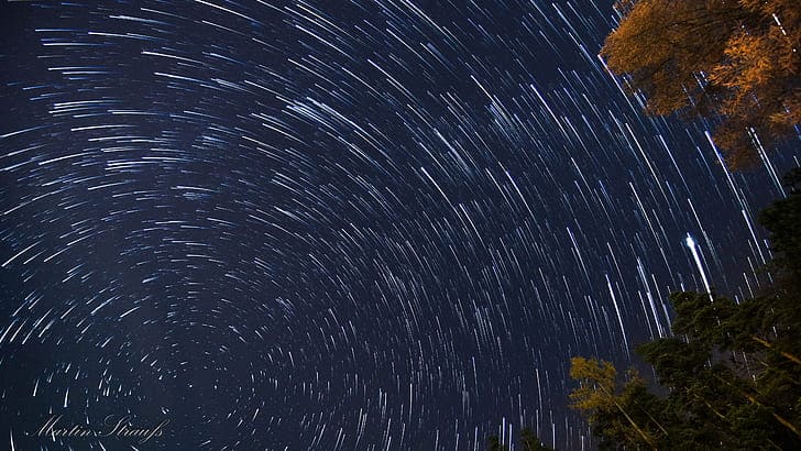 Long-exposure photo of star trails in the night sky, showing circular streaks of light caused by Earth’s rotation.