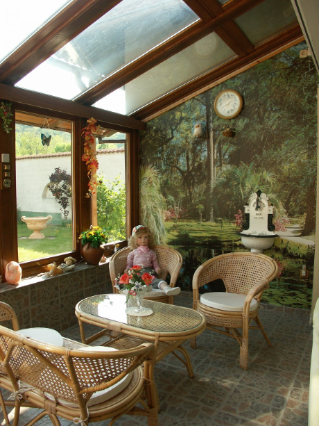 A sunroom with full windows attached to a home wall.