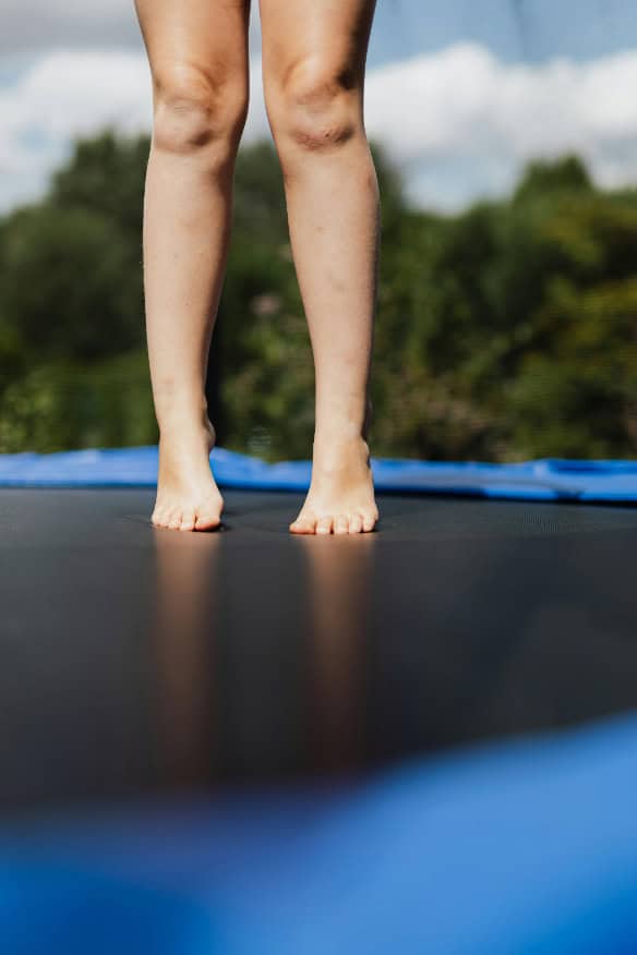 A close-up of a person’s legs and feet on a trampoline.