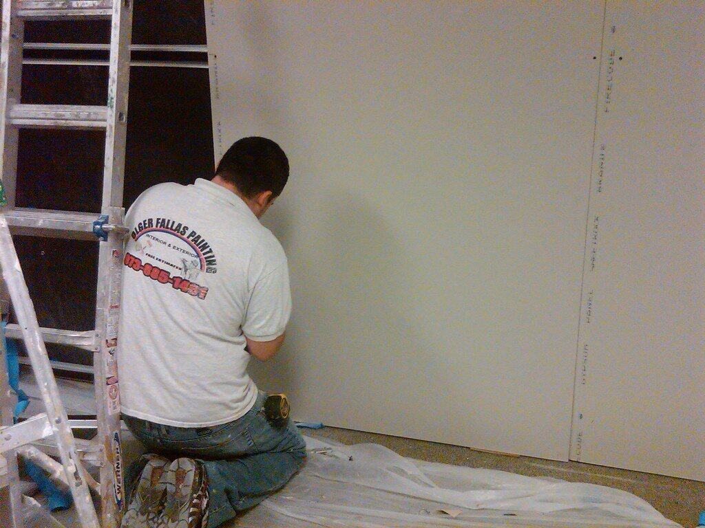 A builder installing drywall.