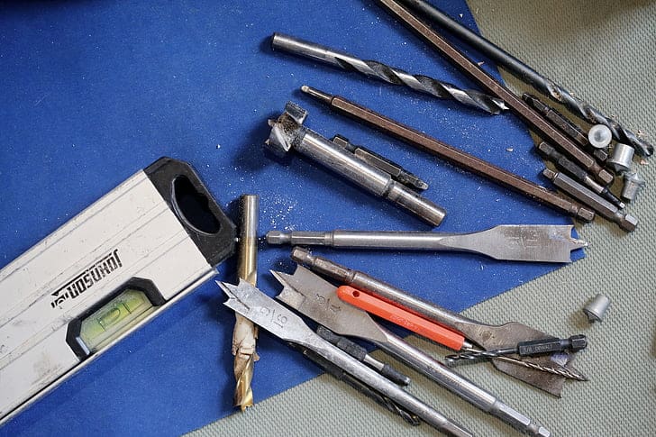 A variety of hand tools and a power drill on a workbench.