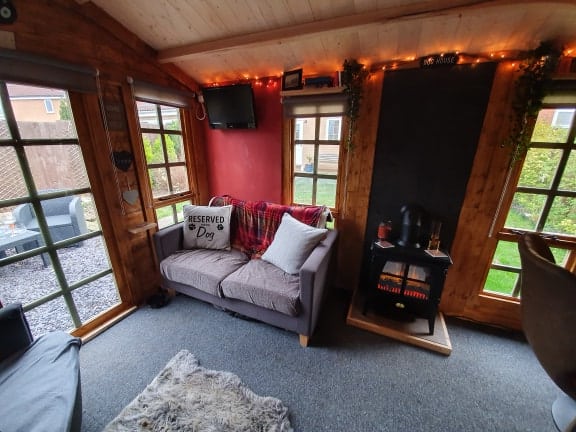 log cabin summerhouse interior with sofas and a wood burner