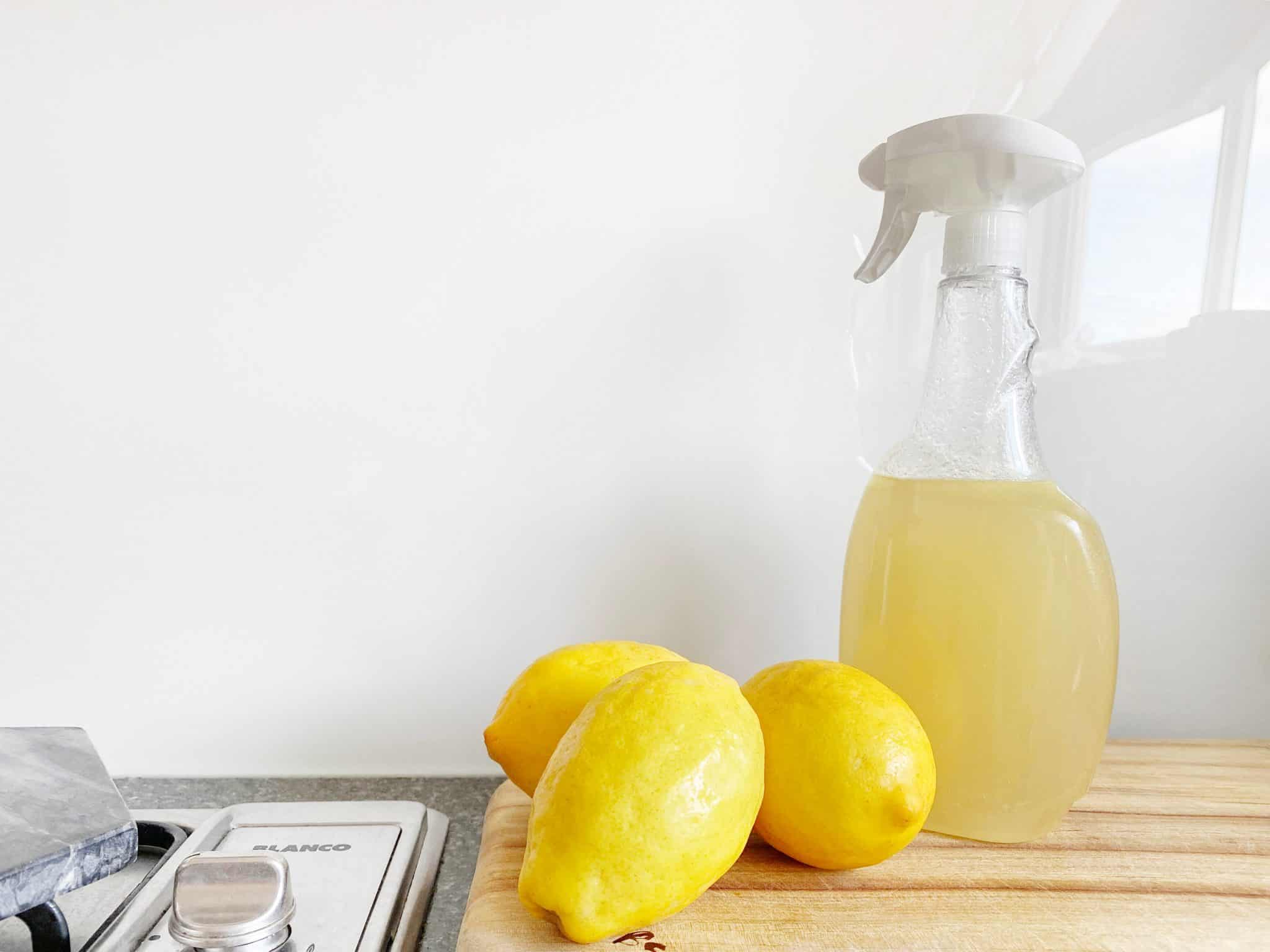 Cleaning Spray Bottle filled with lemon juice and lemons on a chopping board