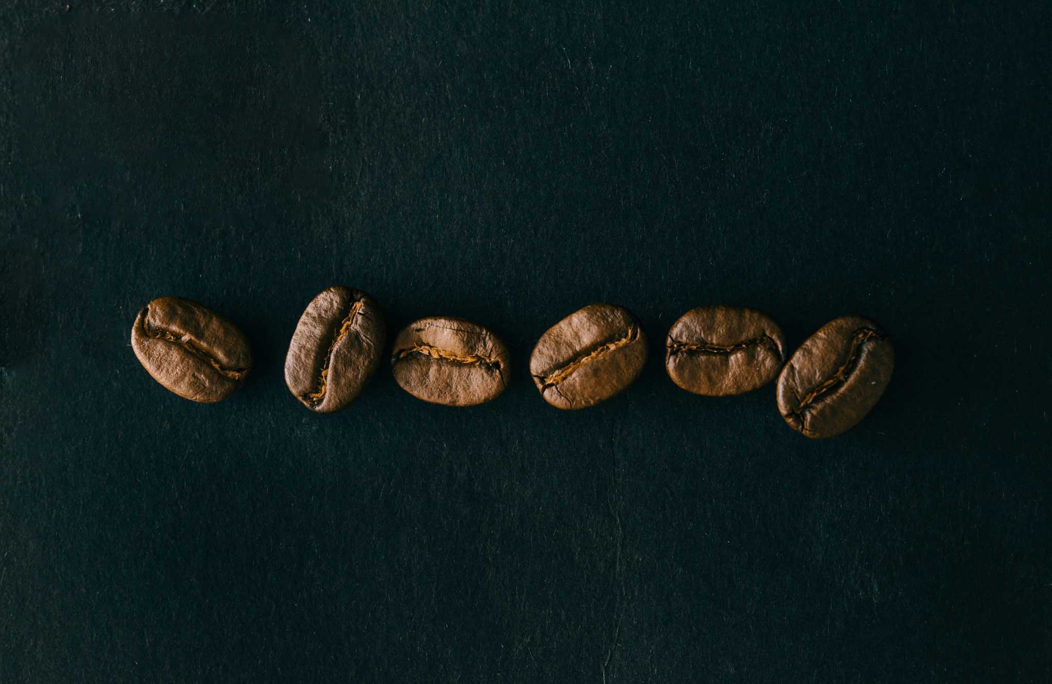 Coffee beans in a row on black background