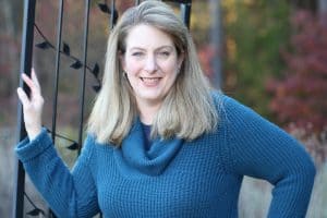 Jeanne Grunert of Home Garden Joy leaning against a gate and smiling