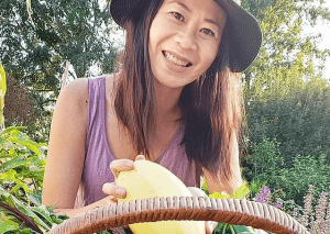 Jo Jo Yee of Jo Jo Garden Cook Smiling holding a vegetable