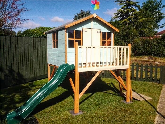 Tower playhouse with flag and slide on grass