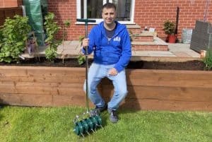 John Moore of Pyracantha sat on a planter holding a garden tool