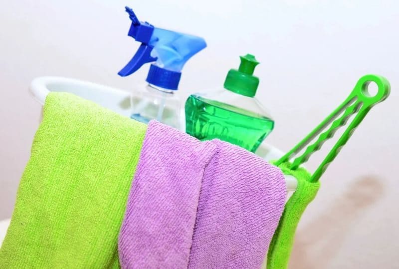 cleaning sprays and products in a bucket with blue and purple microfibre cloths