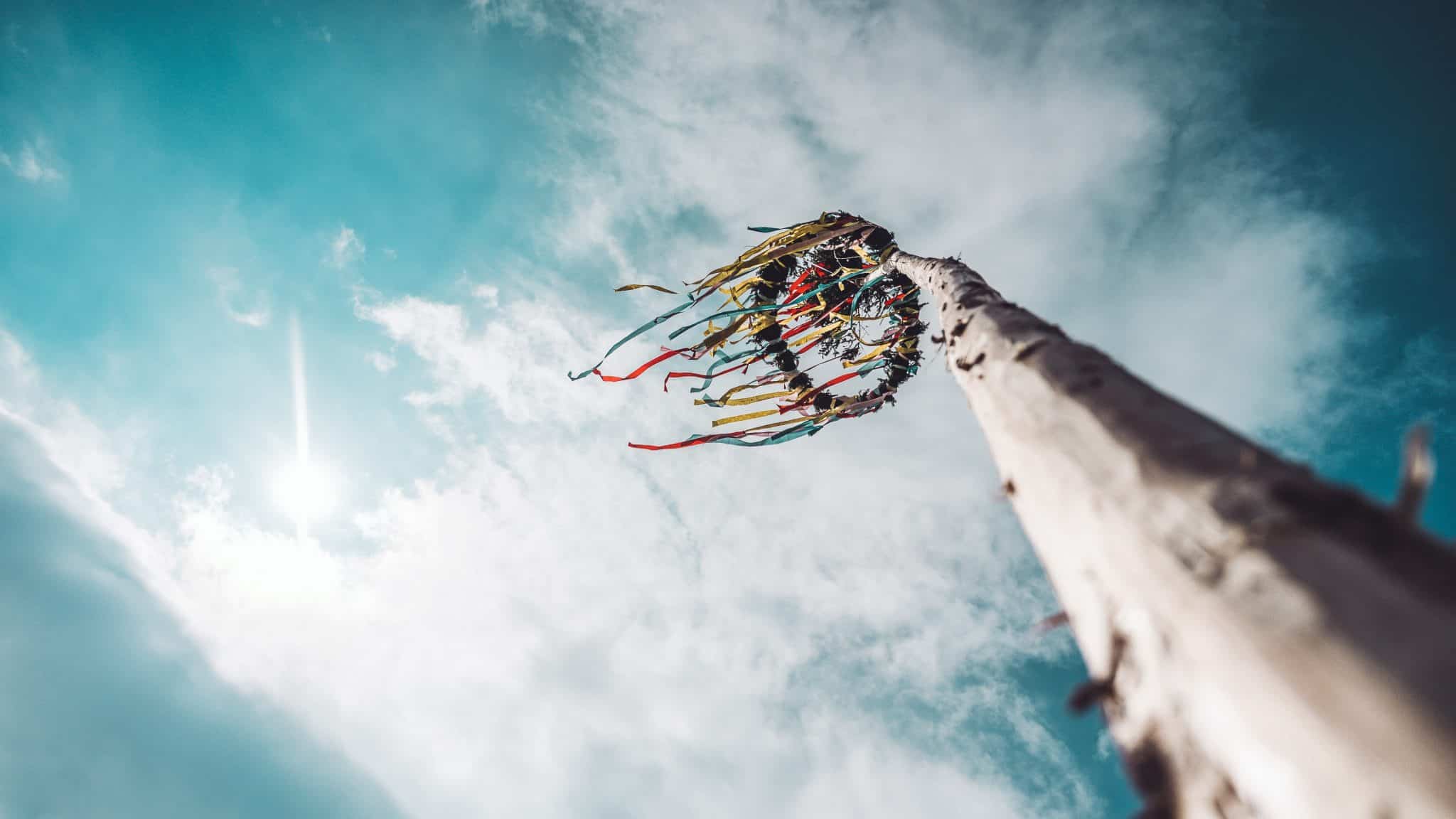 blue cloudy skies looking up from the base at the top of a maypole