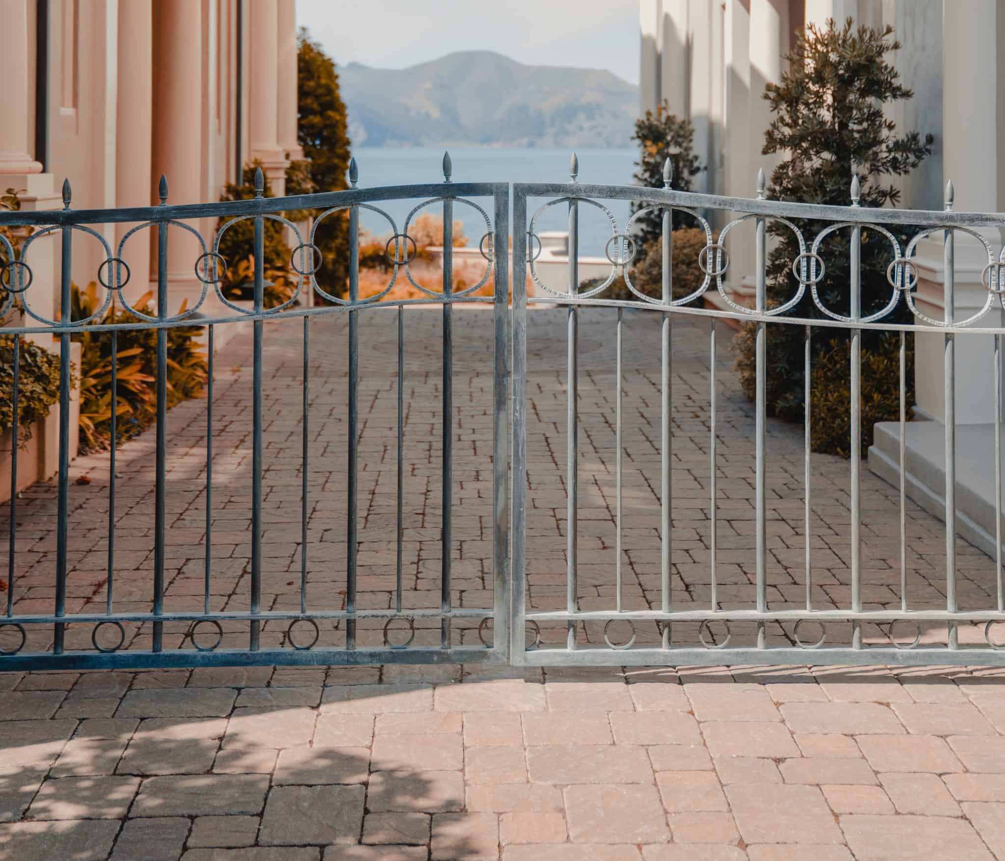 iron gates at the end of a city lane looking past European houses to the sea