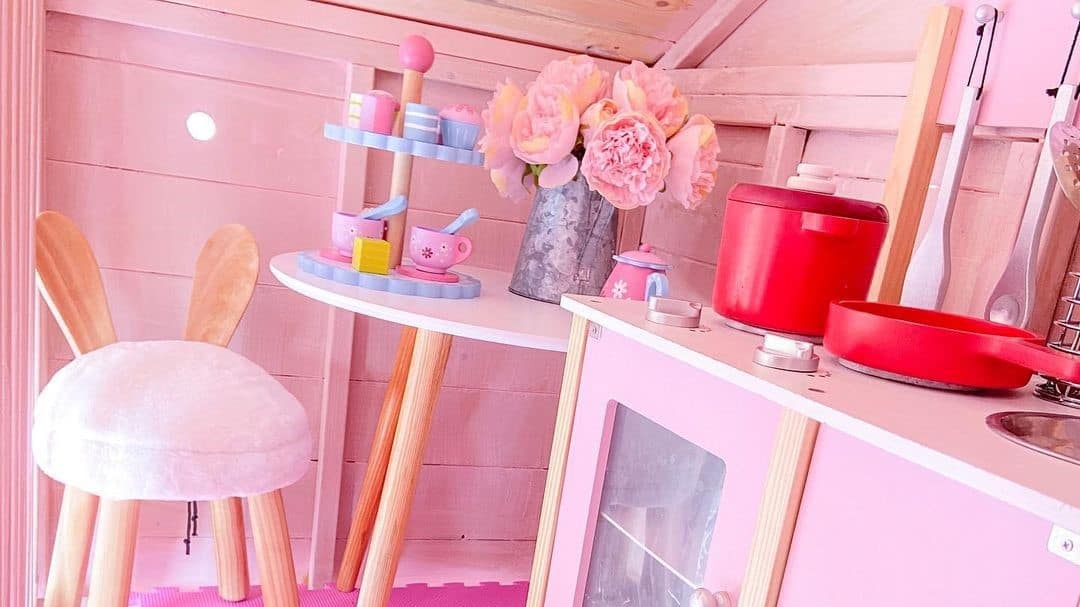 pink playhouse interior with pink cabinets, stool, flowers