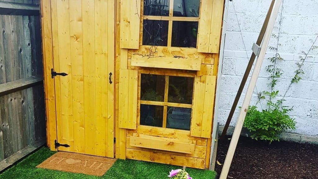 two storey wooden playhouse with stacked windows on astroturf