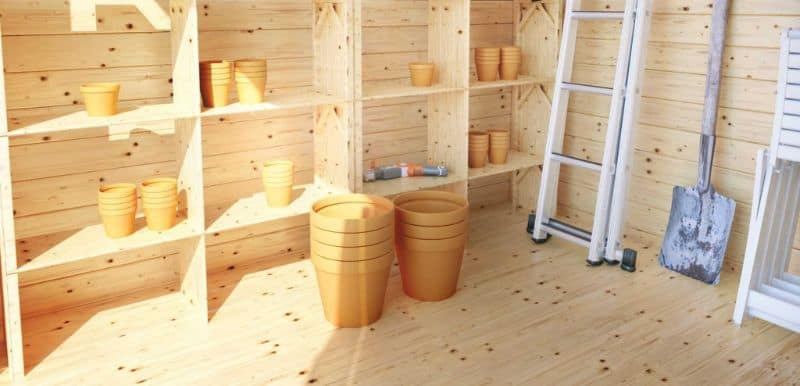 Shed interior with shelving, plant pots, ladder, and spade
