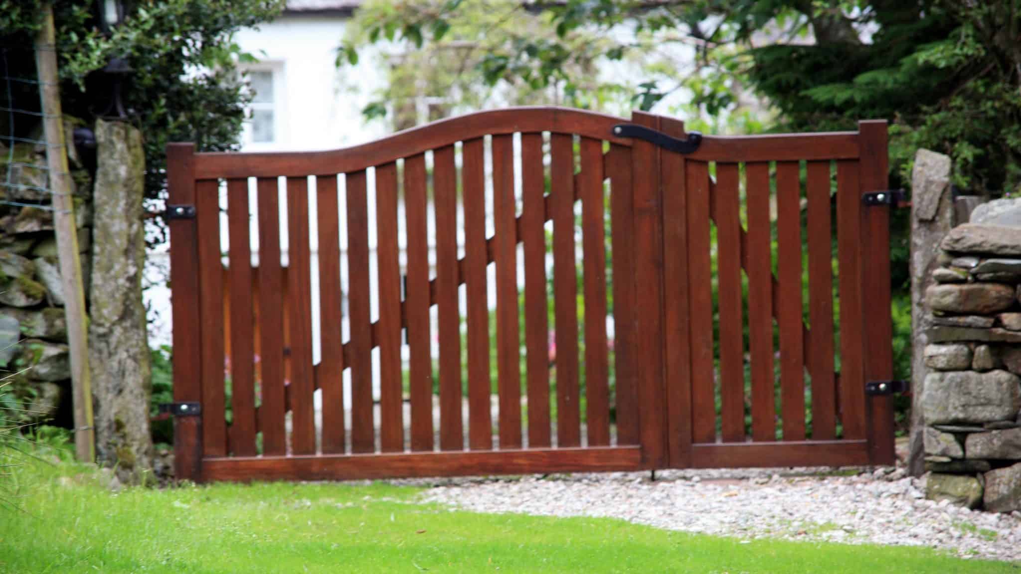 wooden sliding driveway gate on gravel path with lawn